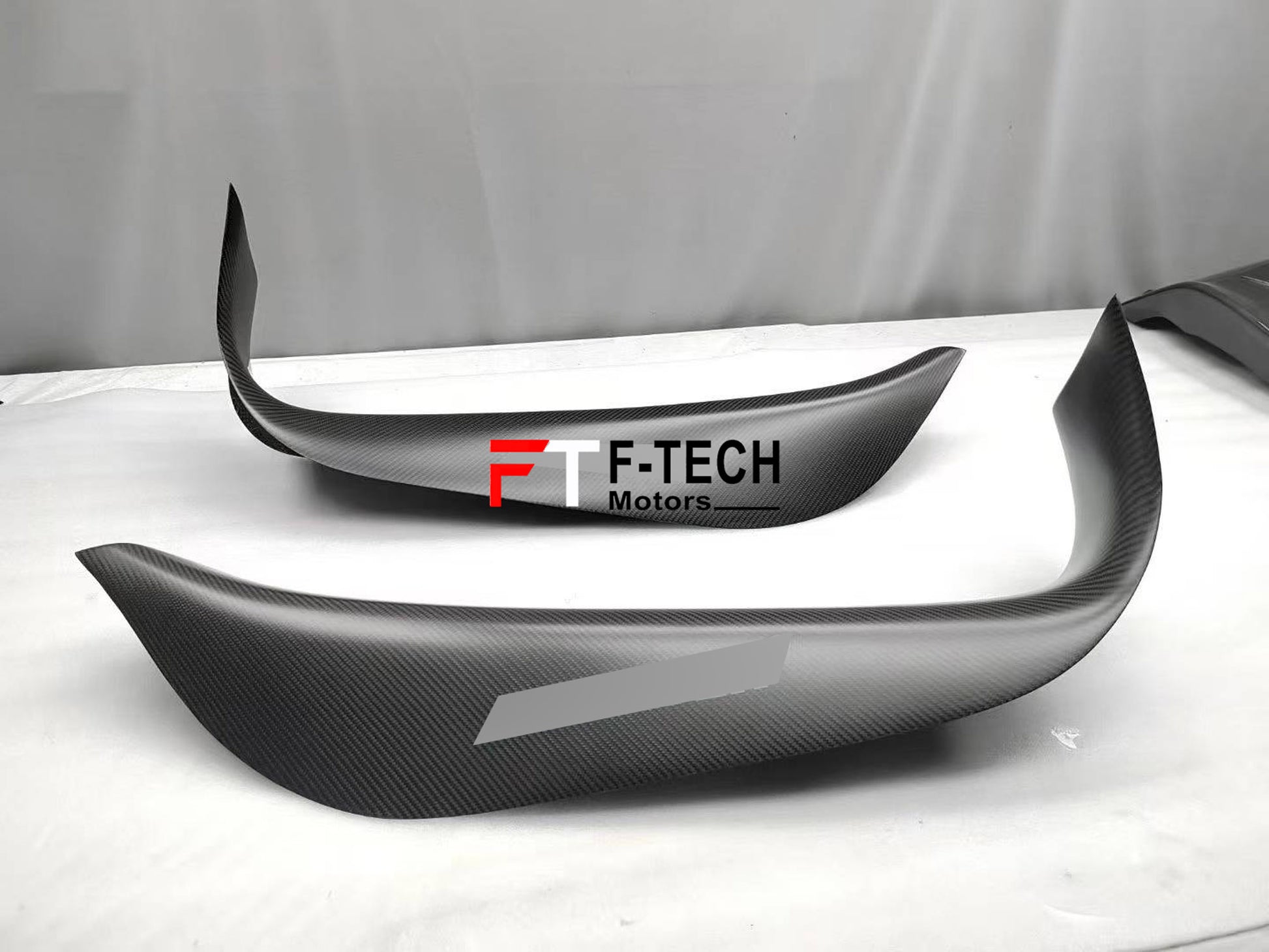 Carbon fiber car wrap with F-Tech Motors logo on a vehicle surface