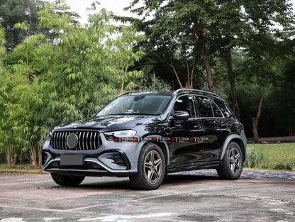 A black Mercedes-Benz GLC SUV parked outdoors on a paved surface with green trees and bamboo in the background. The car has a chrome vertical grille and a visible 'TANK TECH' watermark across the front bumper area.