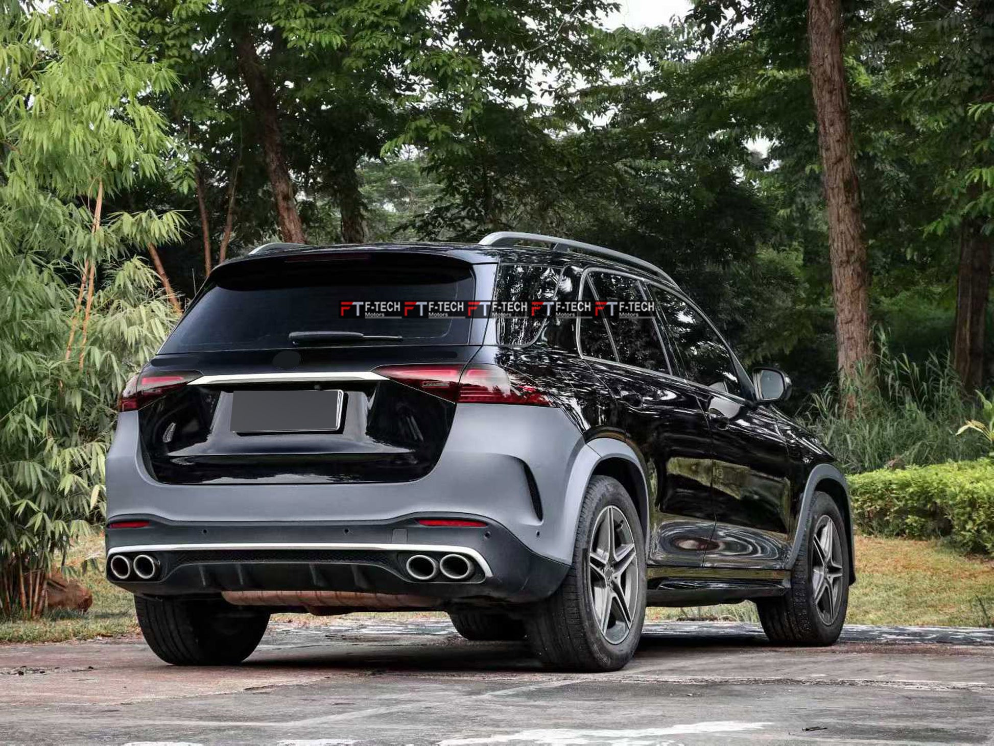 A black Mercedes-Benz SUV shown from the rear three-quarter angle, parked outdoors on a paved surface with trees and greenery in the background.