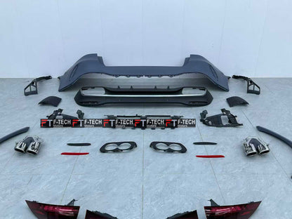 A complete car body kit laid out on a light gray tiled floor against a white wall. The kit includes a black rear bumper, a lower lip spoiler, two exhaust tips, two license plate frames with 'F-TECH' branding, trim pieces, and red-tinted tail light covers.