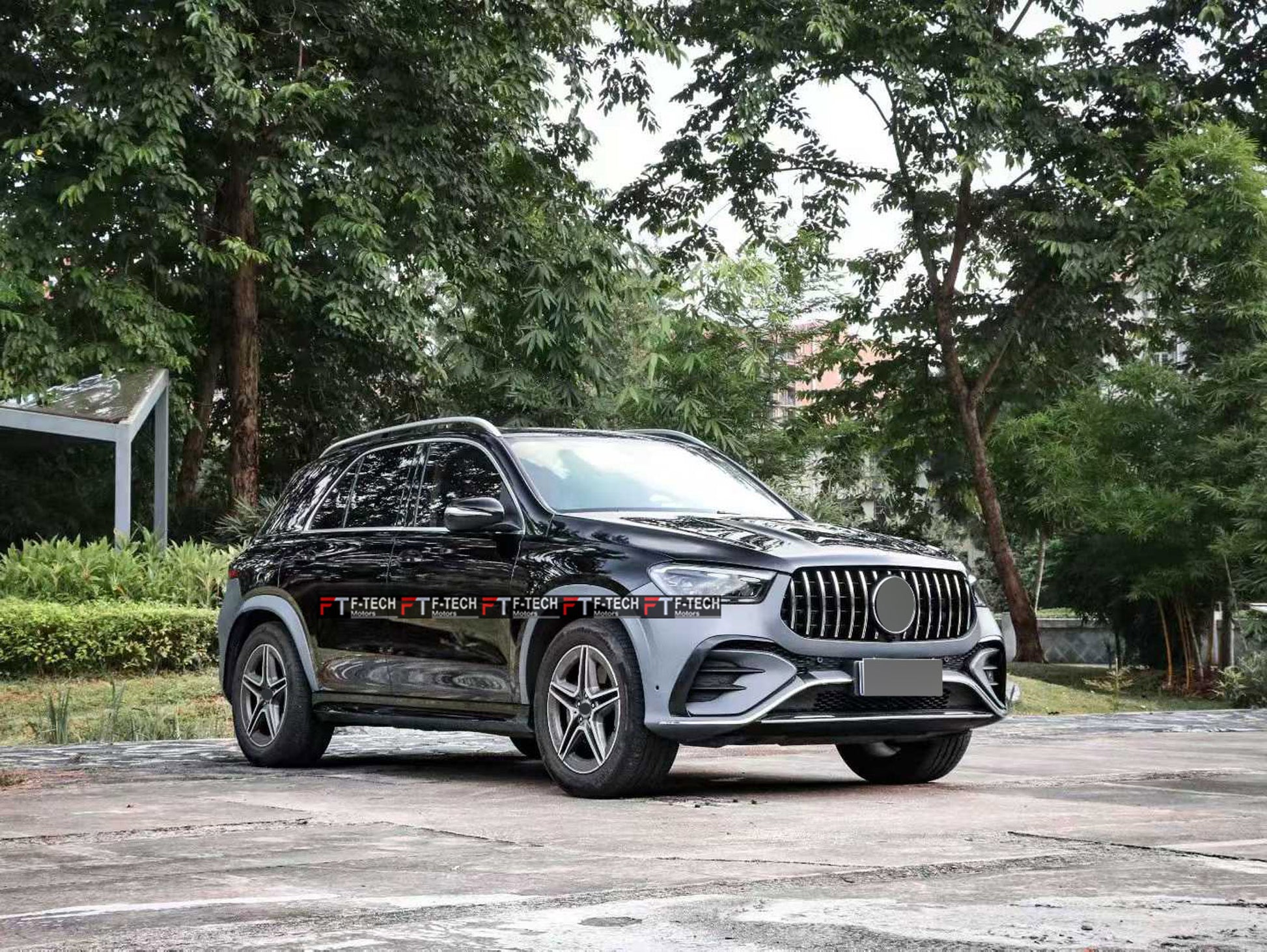 A black Mercedes-Benz SUV parked outdoors on a paved surface with trees and greenery in the background.